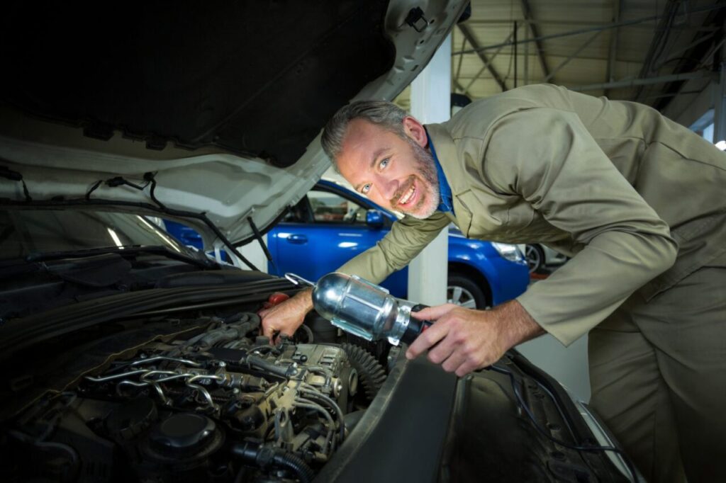 Mécanicien installant un turbo hybride dans le compartiment moteur d’une voiture.